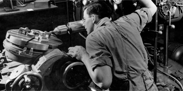 Black and white photo of a man working on an engine